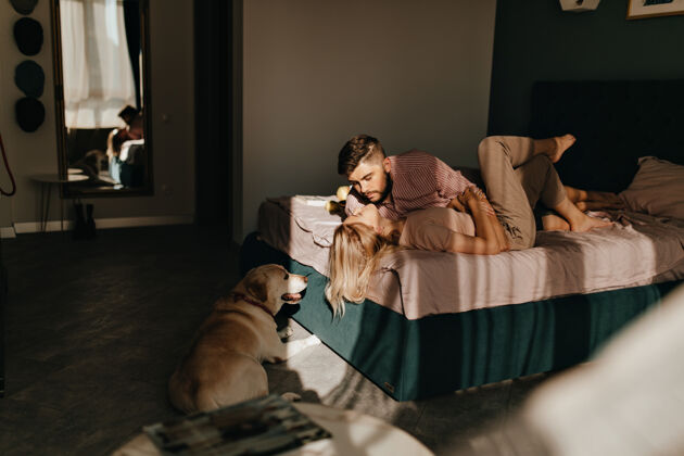情侣早上的一张照片 男人和女人相互欣赏 躺在床上 狗趴在地板上这对夫妇在他们的公寓里享受周末床房子公寓