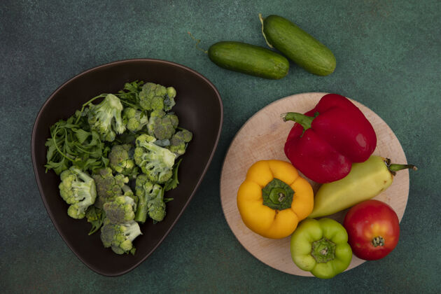 食品顶视图彩色甜椒与番茄的立场和黄瓜与西兰花的绿色背景黄色新鲜绿色
