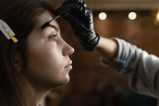 手术女性专家为女性做眉毛治疗的侧视图专家乳胶手套治疗