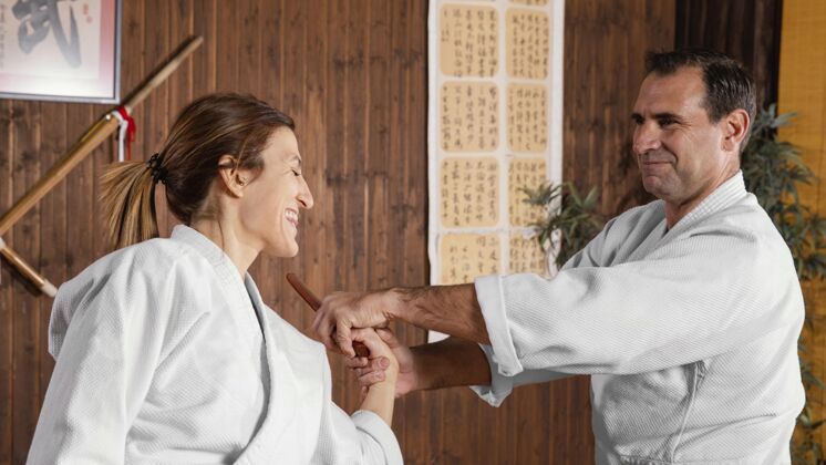 女人微笑男武术教练与女学员在练习厅的侧视图训练教练柔道