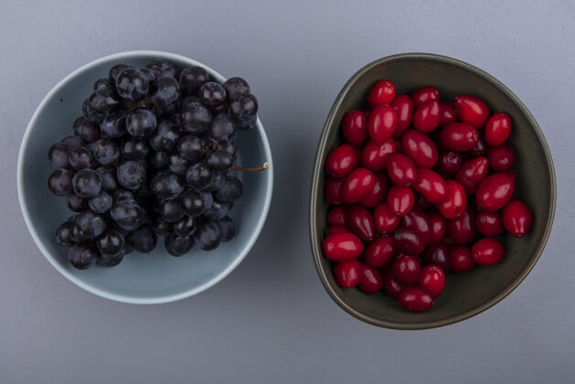 浆果顶视图的水果 如山茱萸和树莓在碗里的灰色背景水果景观山茱萸