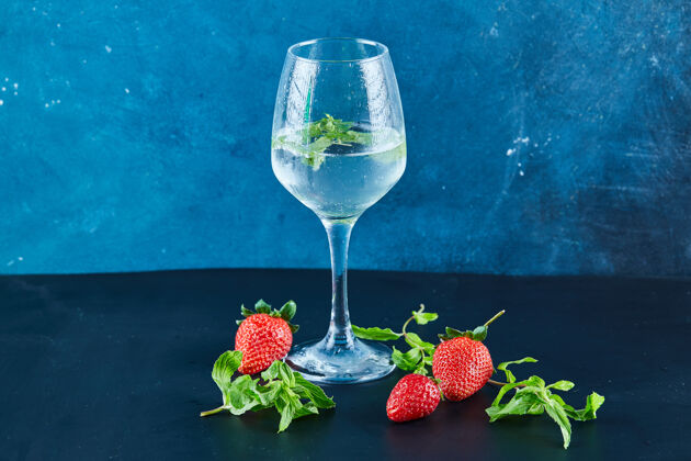 维生素一杯带有薄荷和新鲜草莓以及蓝色表面薄荷的果汁刷新自然新鲜