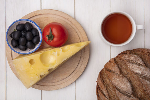 饮料顶视图：一杯茶 放在架子上的番茄橄榄奶酪和一条白底黑面包架子茶面包
