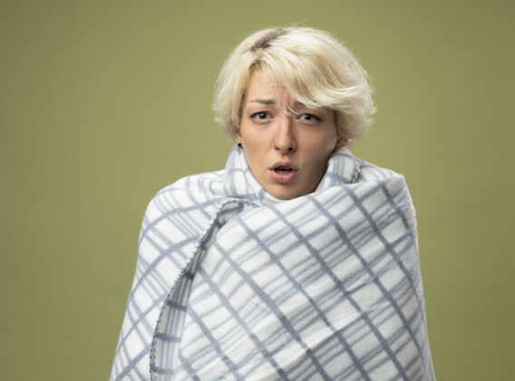 包裹生病的不健康的女人 短发感觉不舒服 裹在毯子里 站在轻质的墙壁上 看起来像患了流感光不健康女人