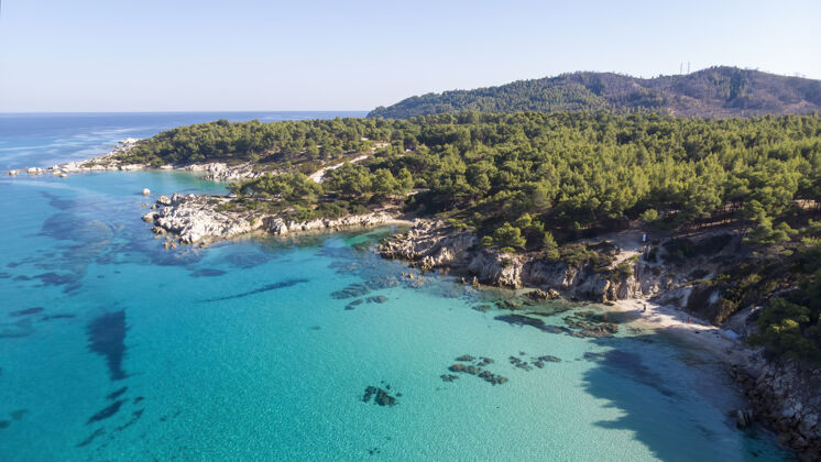 观点爱琴海沿岸有蓝色透明的海水 周围绿树成荫 岩石 灌木丛和树木 从无人驾驶飞机上俯瞰希腊海岸线欧罗巴海景