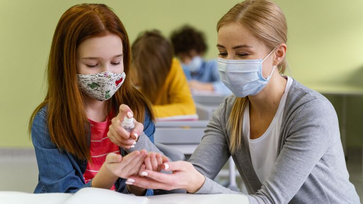 返校戴着医用口罩的小女孩从老师那里拿到洗手液的前视图学习课堂家教