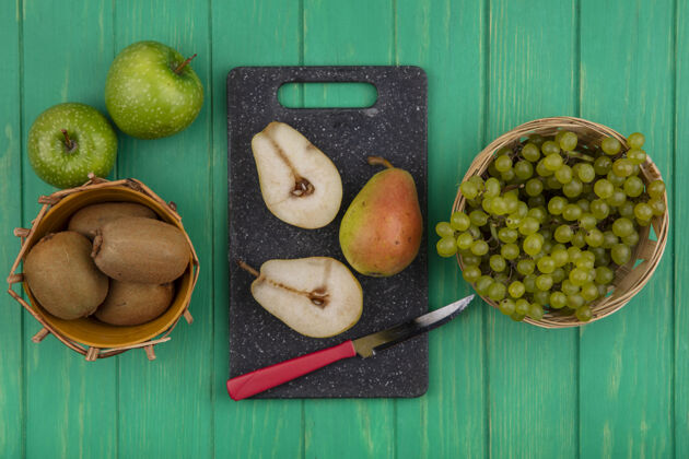 刀顶视图猕猴桃 绿色的葡萄放在篮子里 梨片放在砧板上 绿色的背景是绿色的苹果篮子苹果多汁