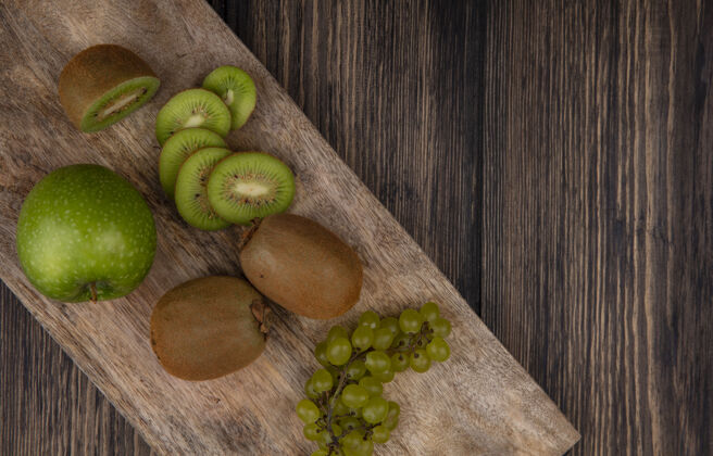 食品顶视图猕猴桃片与绿色苹果和葡萄在一个木制背景上的立场顶部新鲜景观