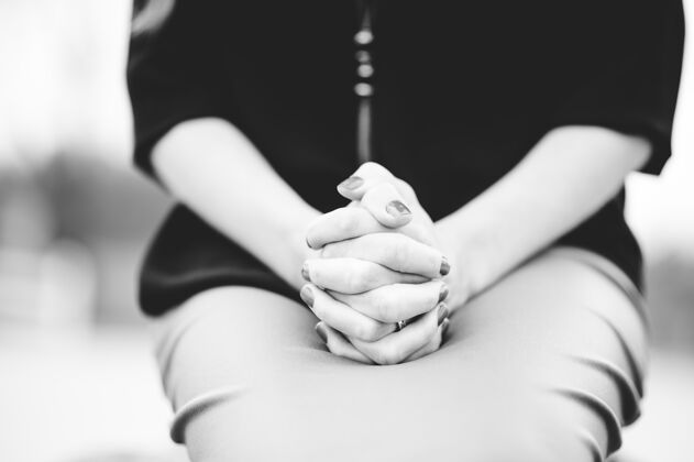 肖像一个女人坐在一起双手放在膝盖上祈祷的灰度图黑发人年轻