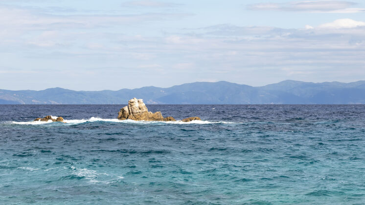 村庄爱琴海的水里有岩石 远处有希腊的陆地乡村风景海岸