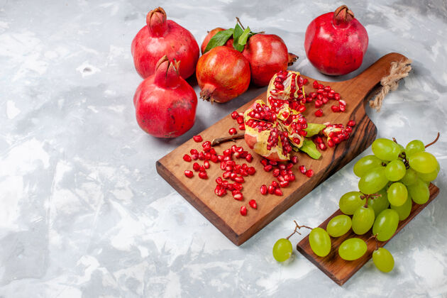 农产品白色书桌上的红色石榴 新鲜多汁的水果和葡萄食物果汁石榴