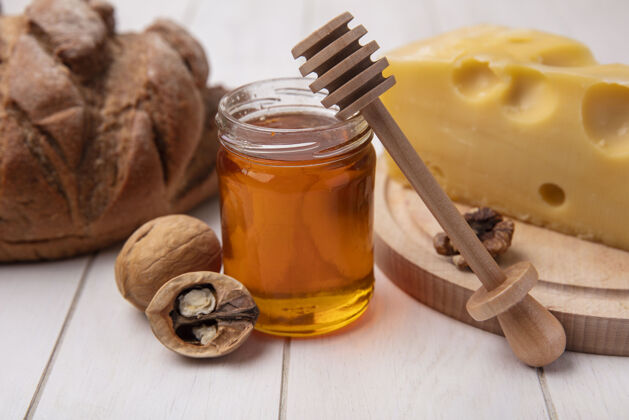 食物前视图蜂蜜与奶酪核桃和黑面包在一个白色的背景罐天然的白的蜂蜜