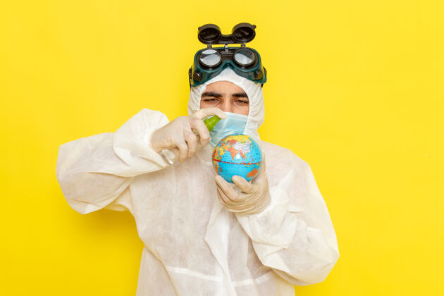 封面正面图：男科学工作者 穿着特殊的衣服 拿着小圆球 把它喷在黄色的表面上服装化学地球仪