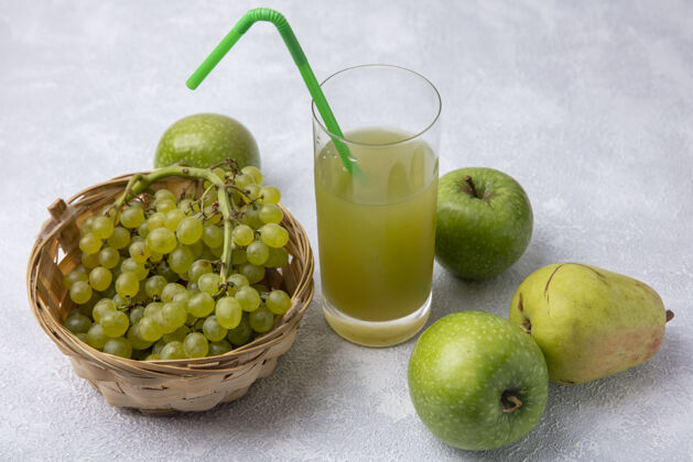 壁板侧视图绿色葡萄与梨绿色的苹果和苹果汁在一个白色的背景玻璃绿色吸管篮子苹果梨葡萄
