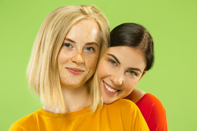 同性恋在绿色工作室背景上 穿着休闲服装的漂亮迷人女孩的肖像两个女模特作为女朋友或女同性恋lgbt的概念 平等 人类情感 爱情 关系女孩年轻微笑