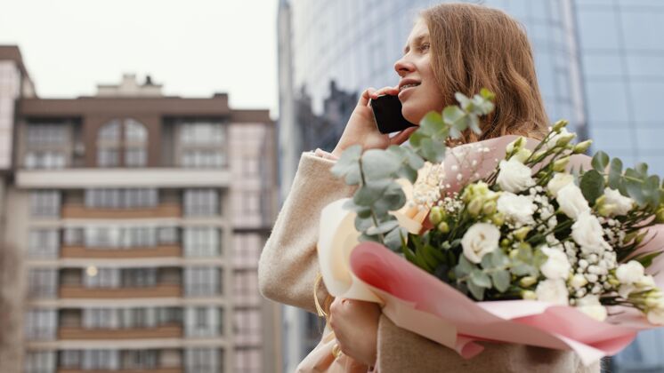 春天优雅的女人在户外打电话 手里拿着一束鲜花季节女人春天