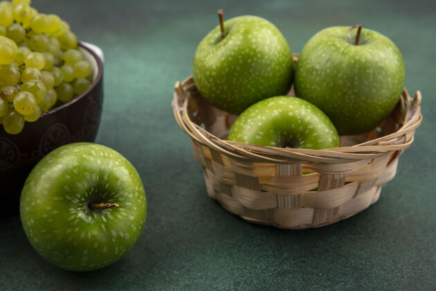 壁板侧视图绿色的背景上有绿色葡萄的篮子里的绿色苹果篮子新鲜苹果