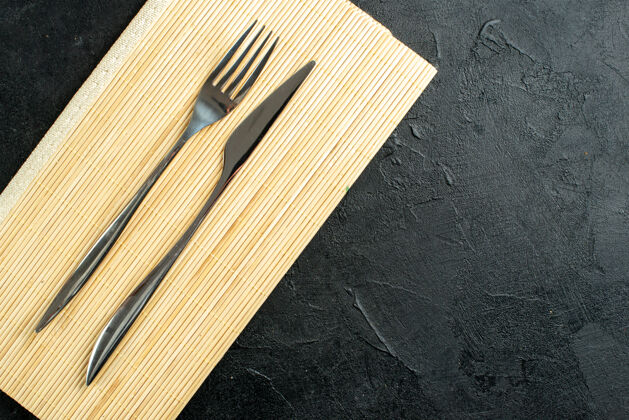 木工顶视图叉子和小刀在米色木板上的黑色桌子上自由活动顶部木工装订