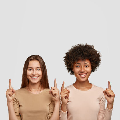 高兴两个食指朝上的不同种族的快乐女性的孤立镜头拍摄垂直朋友