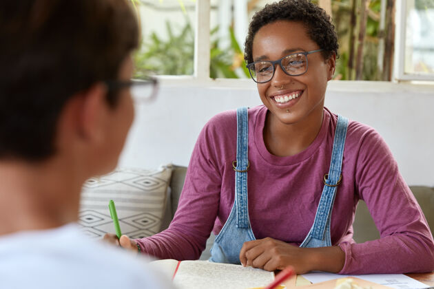 眼镜积极的年轻黑人女记者在眼镜女性同事学习