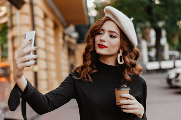 红发迷人的长发女孩在街上用手机自拍神奇的姜女在户外享受咖啡街头风格咖啡拿铁
