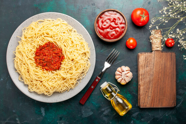奶酪俯视图：深蓝色表面上有切碎番茄肉的熟意大利面食肉切碎意大利菜