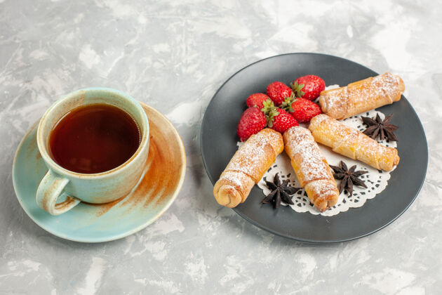 美味草莓和一杯茶的糖粉百吉饼的正面图百吉饼早餐饼干