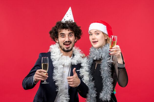 年轻夫妇正面图年轻夫妇在红墙庆祝新年节日圣诞爱情服装庆祝快乐