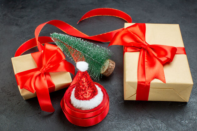 封面俯瞰圣诞老人帽子上的一卷丝带和美丽的礼物圣诞树上的黑暗背景圣诞老人帽子木屐视图