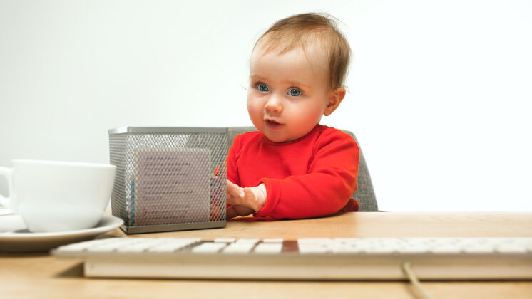 宝贝快乐的小女孩坐在白色工作室里 用现代电脑或笔记本电脑的键盘科技年轻女士