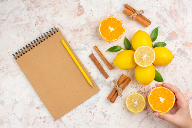 早餐顶视图新鲜柠檬切橘子肉桂棒切橘子在女性手提笔记本铅笔明亮孤立的表面笔记本光明柑橘