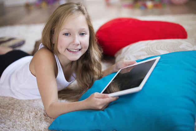 玩微笑的女孩拿着一个数字平板电脑下来深情玩