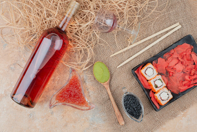 酒一瓶葡萄酒 酒杯和寿司放在粗麻布上杯子桌子绳子