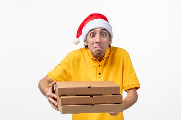 工作正面图：男快递员拿着披萨盒在白色墙上工作 服务制服新年职业制服盒子
