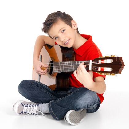 微笑帅气的快乐男孩正在弹原声吉他-白色背景上孤立吉他乐器坐