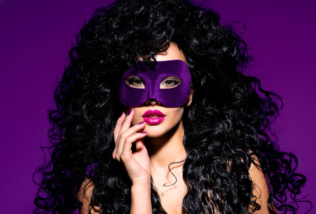 黑色的头发一个美丽的女人的肖像 黑色的头发和紫色的戏剧面具在脸上紫色的指甲卷曲发型女人