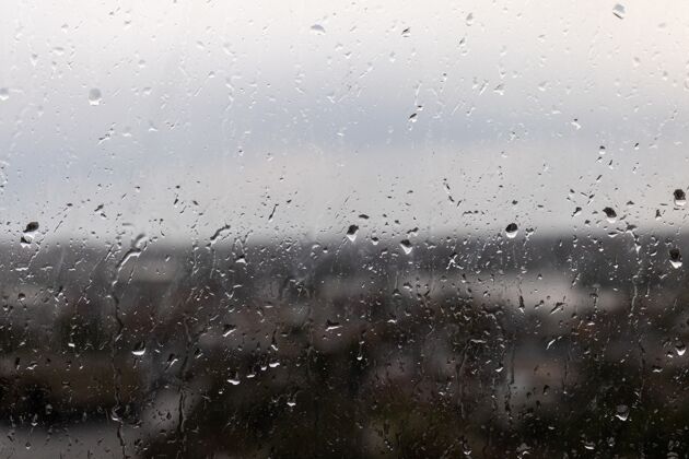 湿一个阴雨天窗户的特写镜头 雨点从窗户上滚下来季节水雨