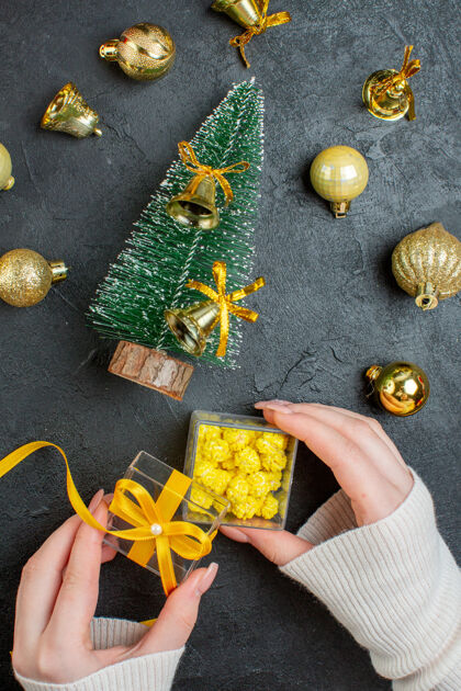 谷物手持礼品盒和圣诞树装饰配件在深色背景下的垂直视图景观种子水果