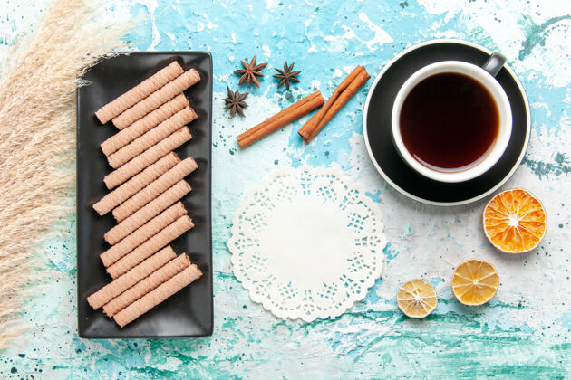 派顶视图甜甜的长饼干与一杯茶和肉桂蓝色背景卷笔刀长茶