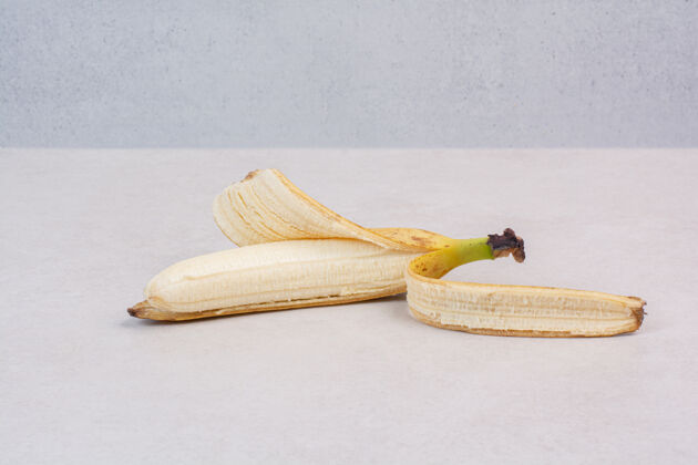 成熟在白色的桌子上剥一根香蕉香蕉天然去皮