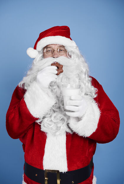 节日饥饿的圣诞老人在摄影棚吃饼干休息活动庆祝