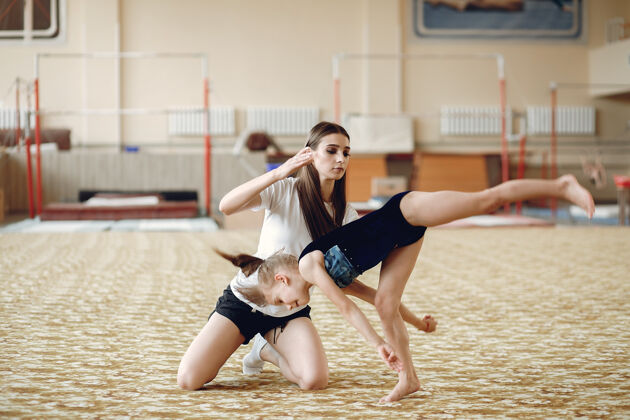 年轻指导学生女体操运动员 进行各种体操练习和跳跃儿童和体育 健康的生活方式灵活体操运动员健身