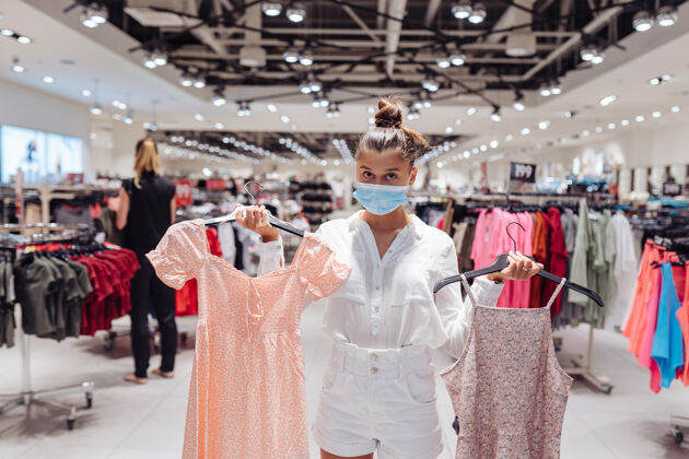 衣服年轻女子在服装精品店购买带有防护面罩的服装商店流感检疫