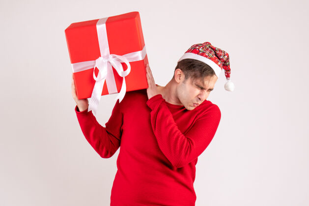 丝带前视图吓坏了一个戴圣诞帽的年轻人站在白色的地板上盒子礼物成功