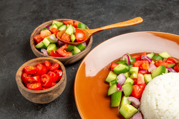 盘子在黑暗的桌子上 用米饭和不同种类的蔬菜近距离观看素食晚餐密切营养番茄
