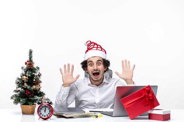 树戴着滑稽圣诞老人帽的年轻商人对他在办公室听到的消息感到震惊帽子年轻商人听说