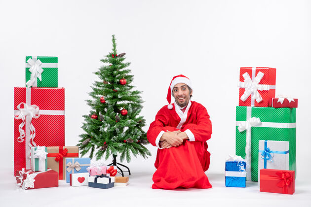 人年轻人打扮成圣诞老人带着礼物和装饰圣诞树圣诞老人打扮礼物