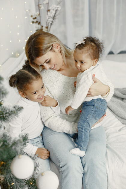 女人人们在为圣诞节做准备母亲在和女儿们玩耍一家人在节日的房间里休息孩子穿着毛衣亮光国际传统