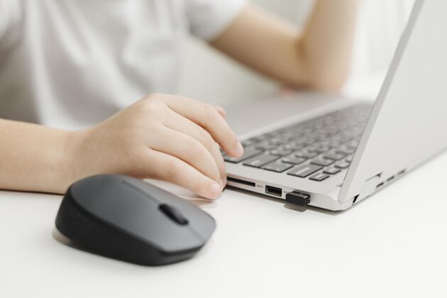 数码设备侧视图儿童使用笔记本电脑和鼠标设备男性男孩