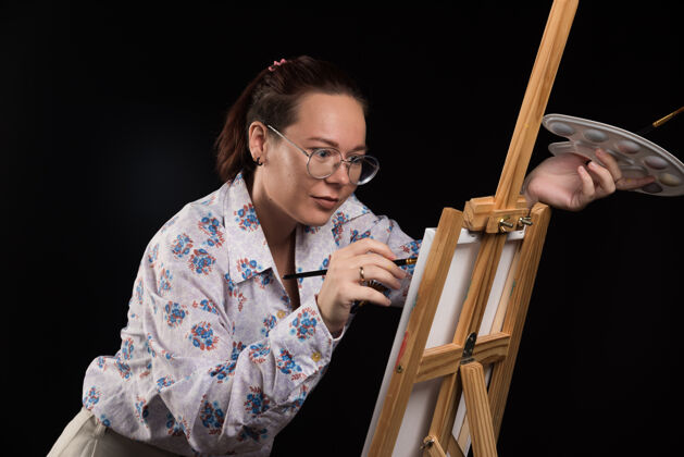 手女画家用铅笔在画布上画一幅画 背景是黑色的艺术绘画女孩